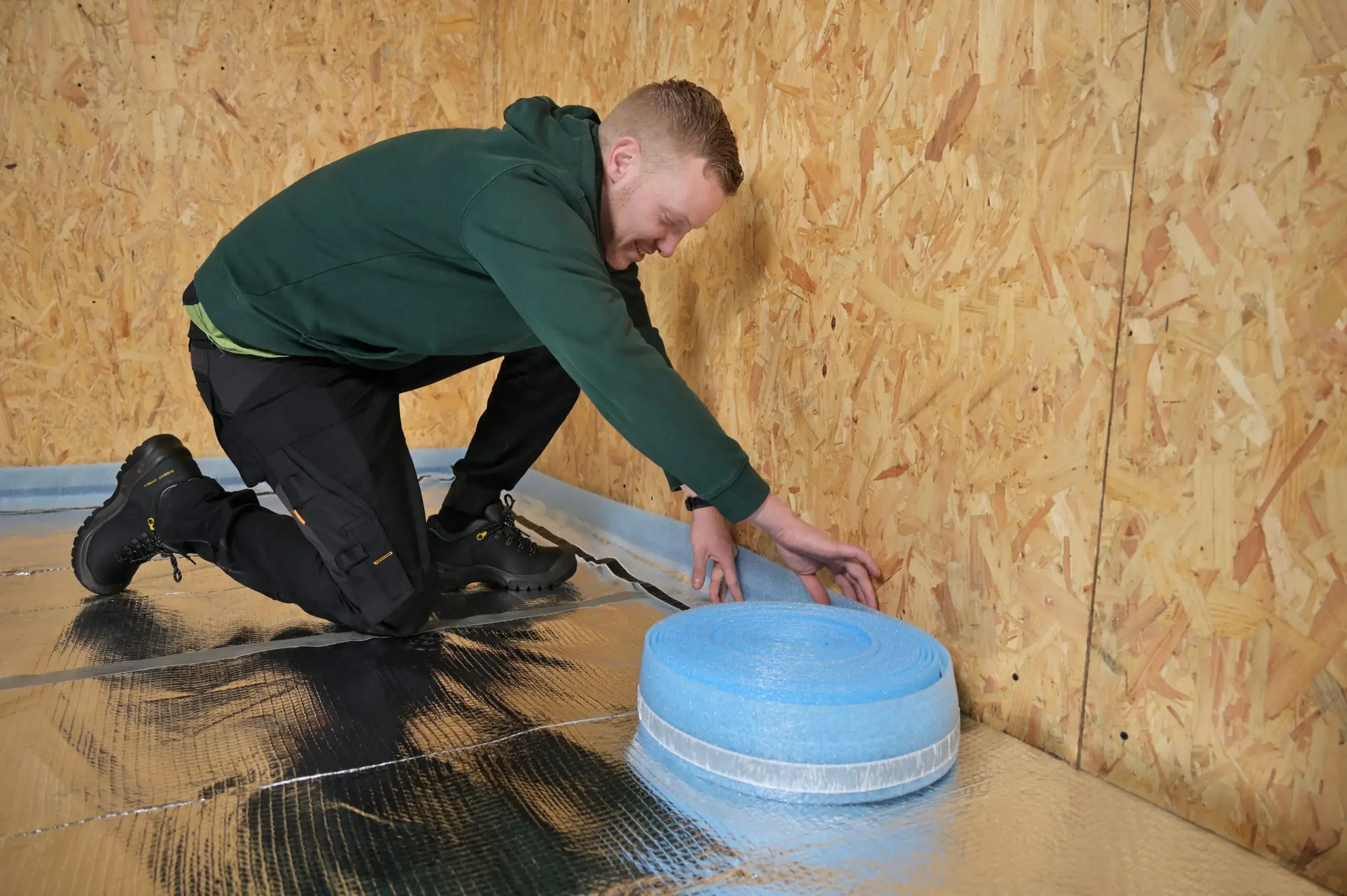 The installer is placing edge insulation around the wall.